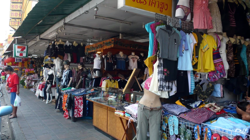 a market area with colorful shirts hanging from the roof