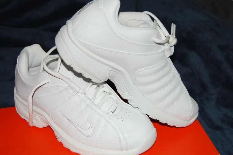 a pair of white sneakers on top of an orange mat