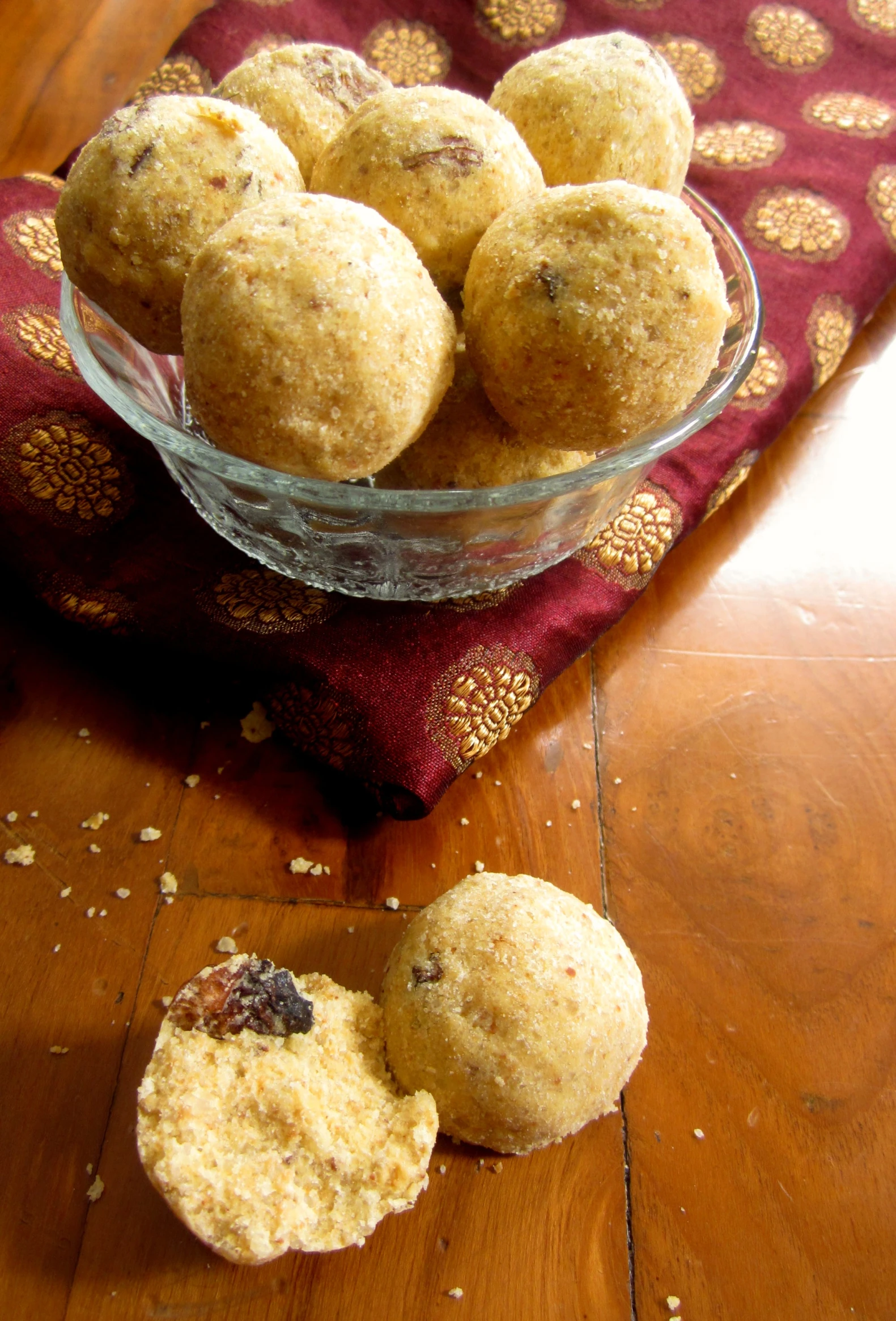 a bowl of muffins sits on a red fabric next to some cut in half muffins