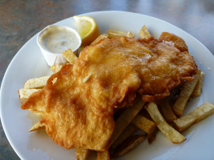 fish and chips sit on a plate with lemon wedges