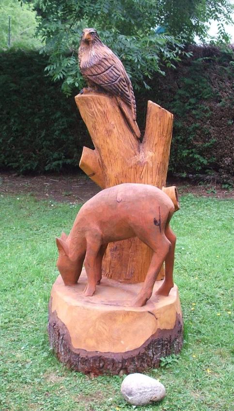 a wooden statue of a bird sitting on the side of a tree trunk