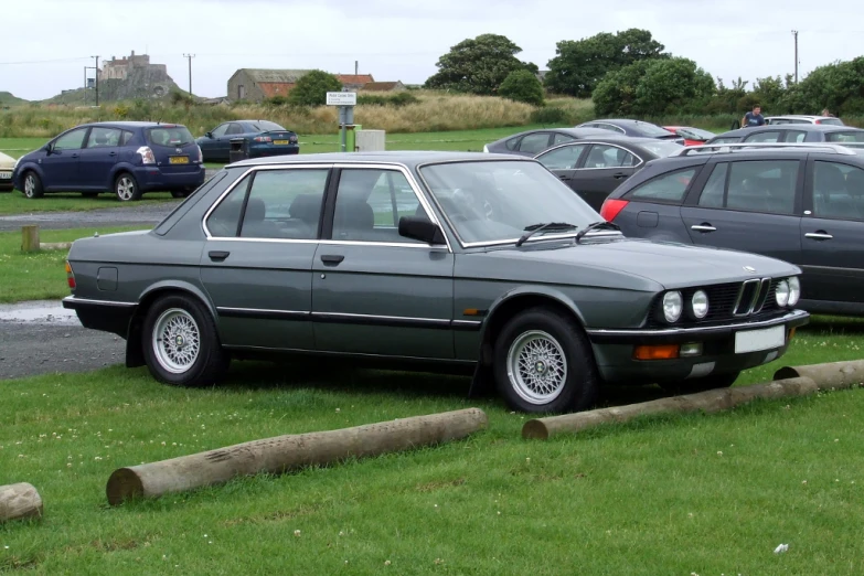 some cars parked on the grass near a parking lot