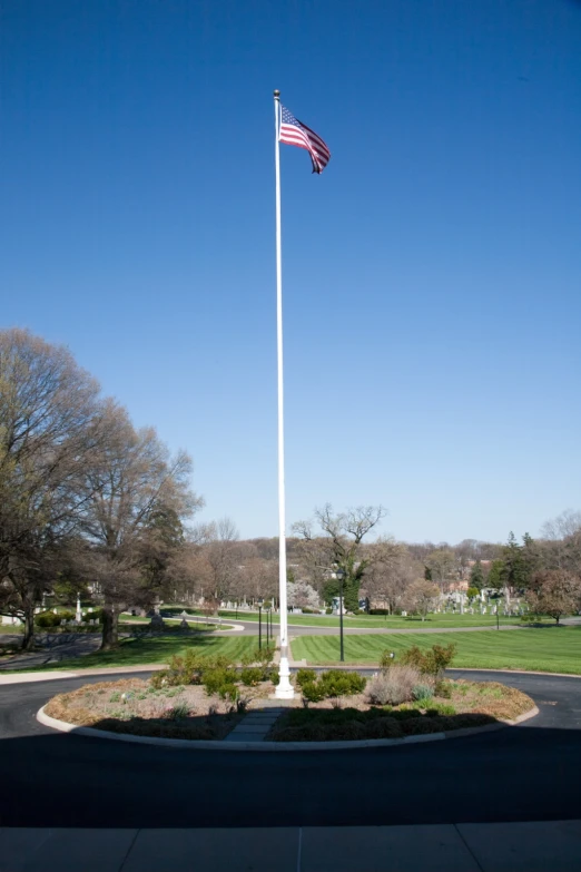a flag on top of a white pole in a park