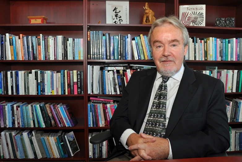 the man in the suit is standing next to a bookcase