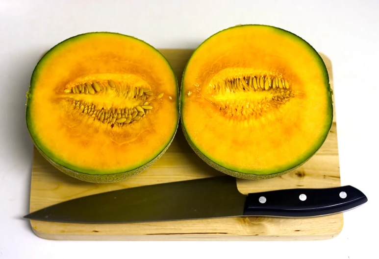 two yellow squash on a  board next to a knife