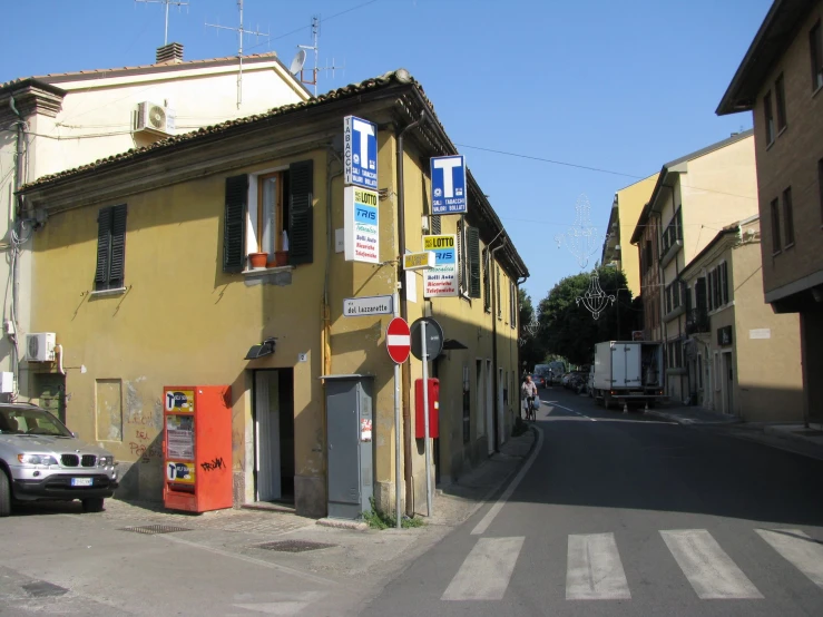 a long narrow street with yellow buildings and signs on the building's windows