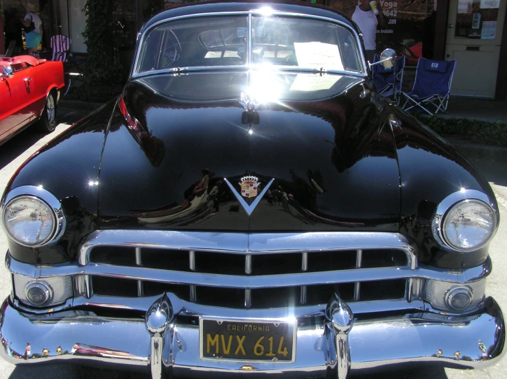 the front end of a classic car parked on the sidewalk