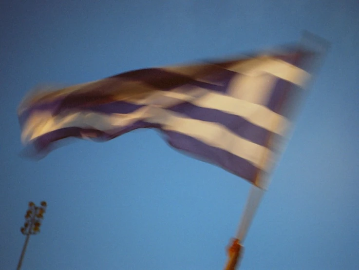 a large waving flag in the air near a field