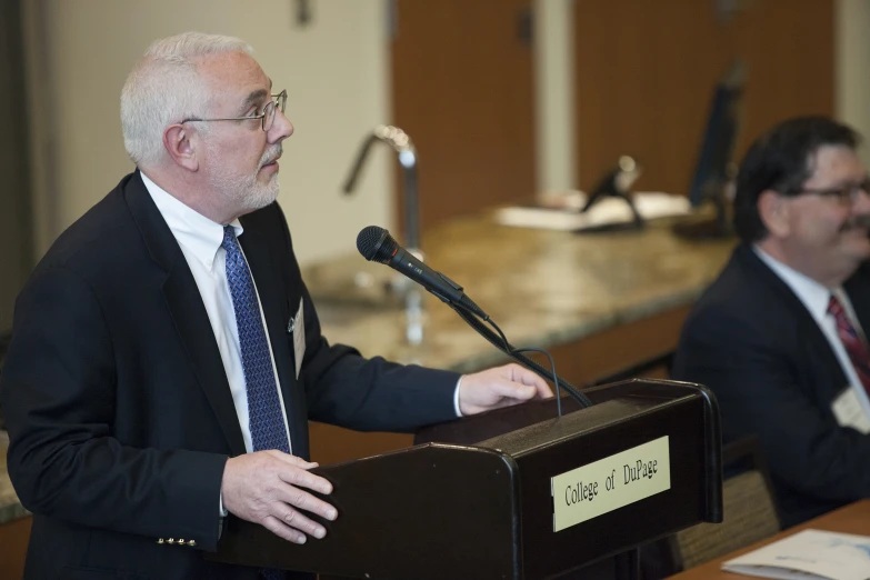 an older man is giving a speech in front of other people