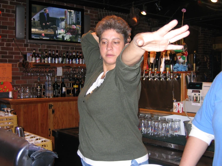 woman with hand raised over bar at indoor restaurant