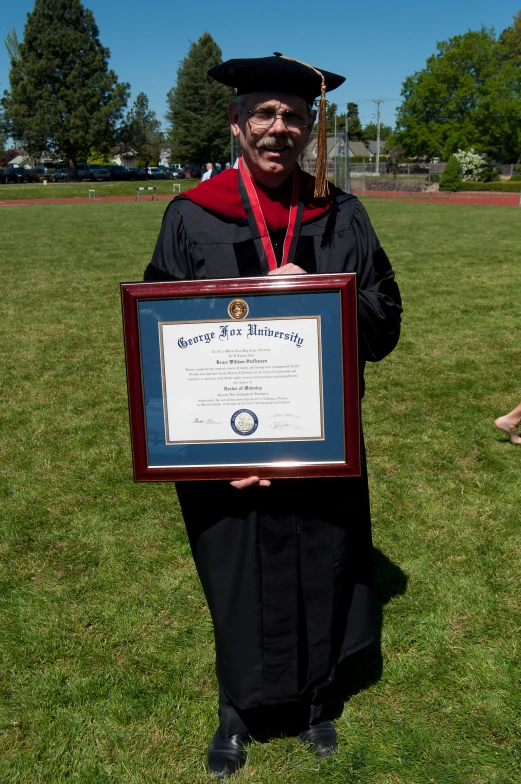 a person holding a framed award standing in a field