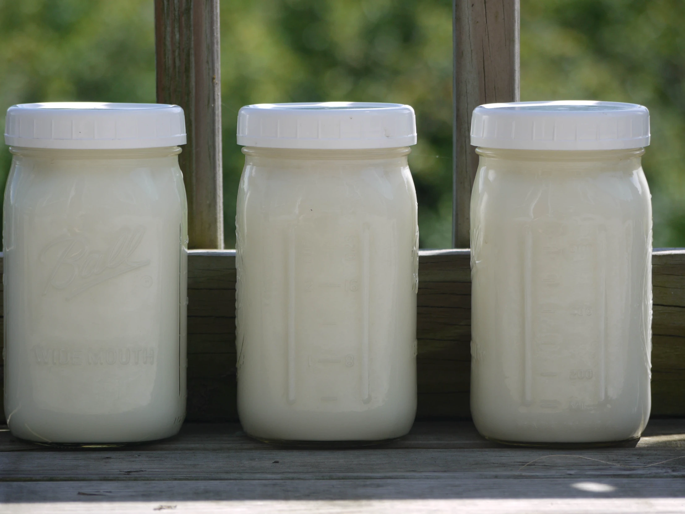 three large mason jars sitting on a porch