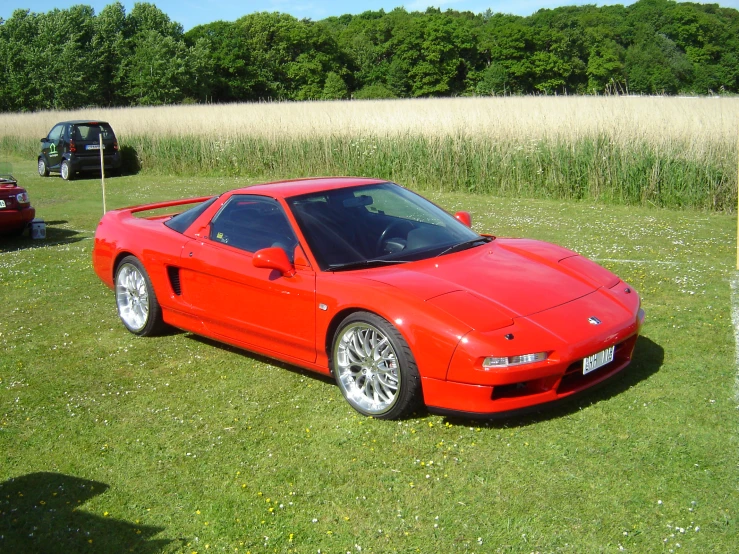 a red sports car is parked in a grassy field