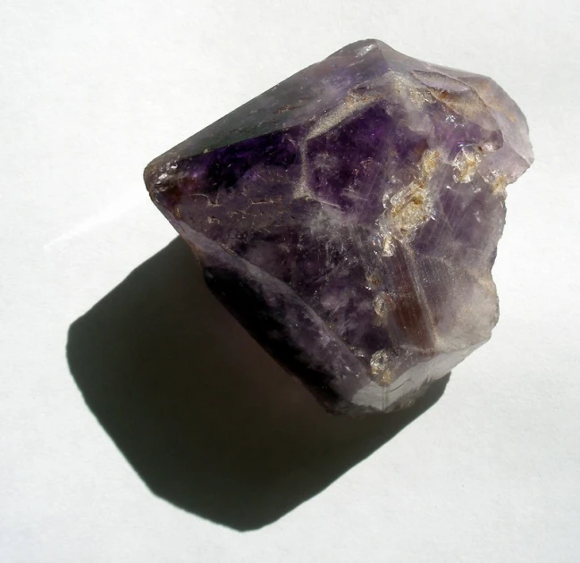 a piece of purple rock sitting on top of a white table