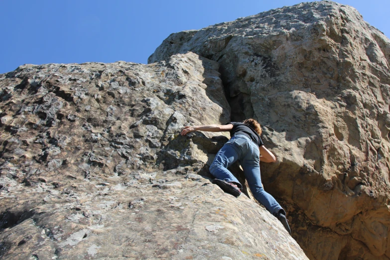 a woman climbs a rock while another climbs from the top