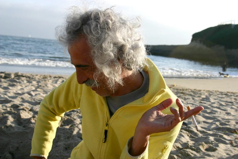 an old man stands at the beach with his fingers in the air