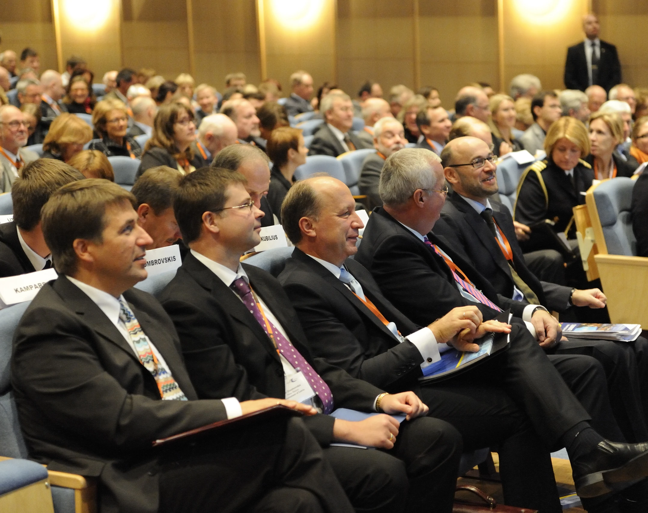 several people in suits sit side by side in a conference room