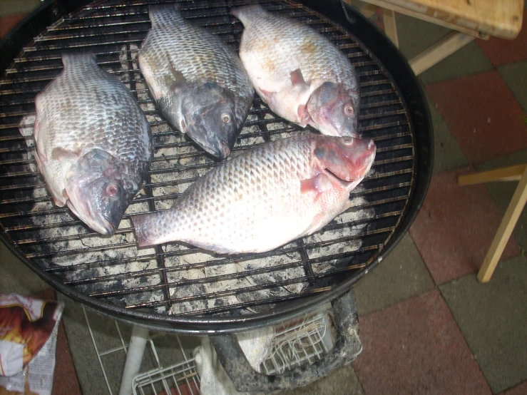 five fish are on the grill grill, being cooked