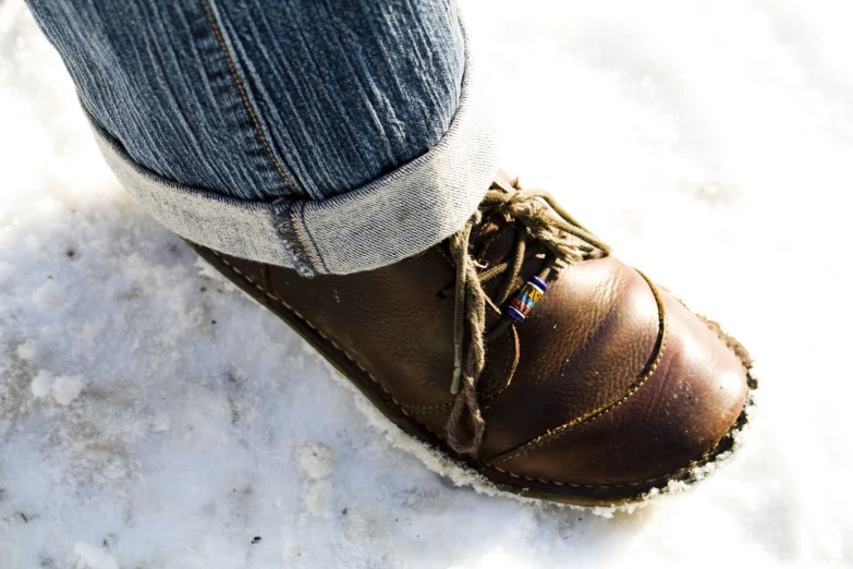 a person wearing blue jeans and brown leather shoes