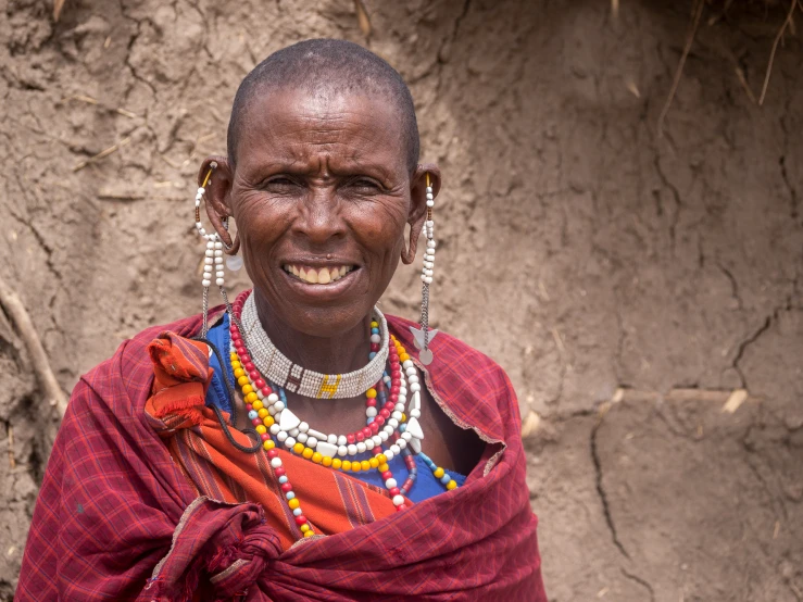 an older woman in traditional clothing stands on dirt