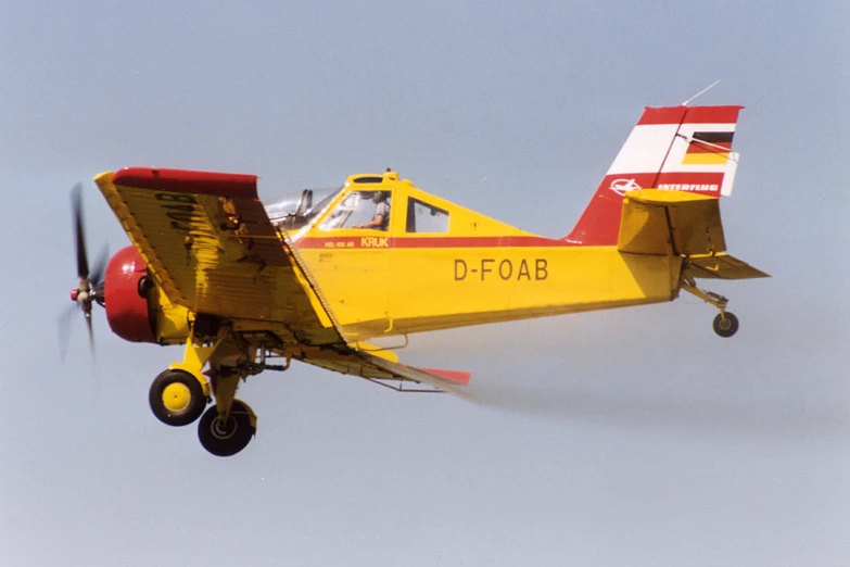 a small yellow plane flying through the sky