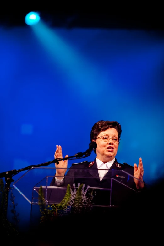 a woman in suit and tie making speech
