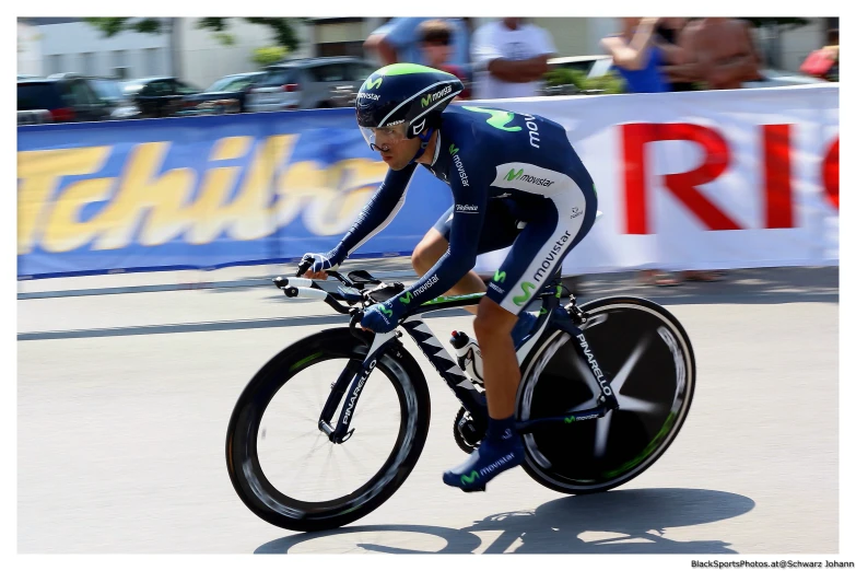 there is a male bike racer riding down the street