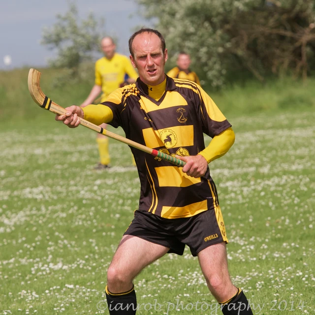 a man in a yellow and black soccer uniform with a stick in hand