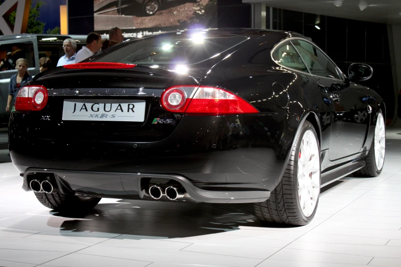 an all black car on display with people around it