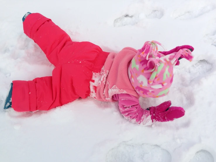 baby in pink and pink clothes laying in snow