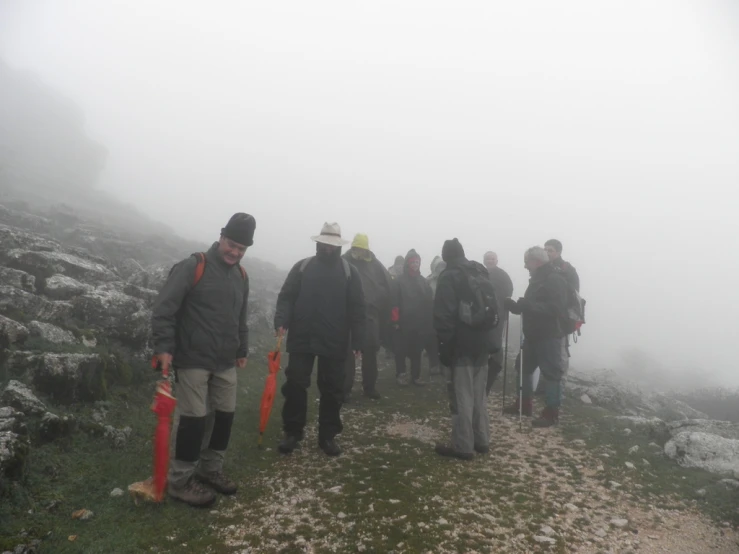 a group of people hiking through the fog on a hillside