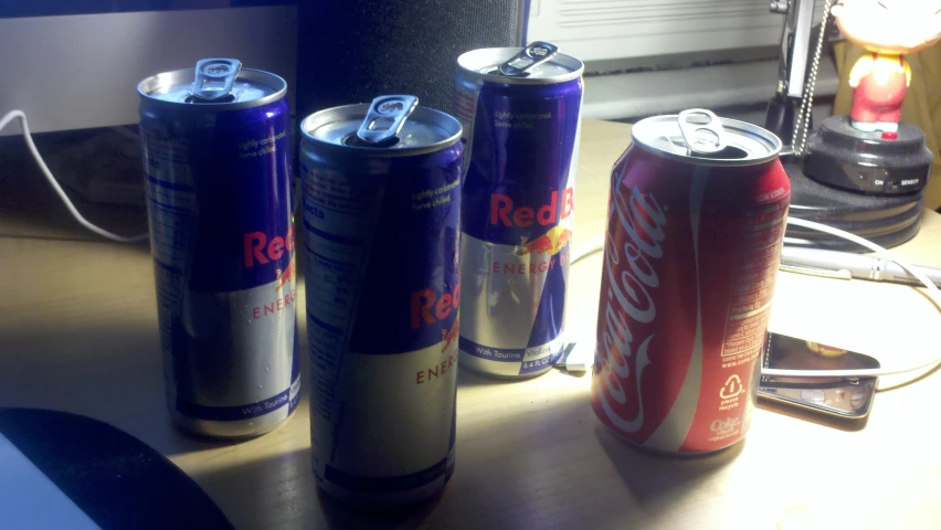 three cans of soda are on a desk