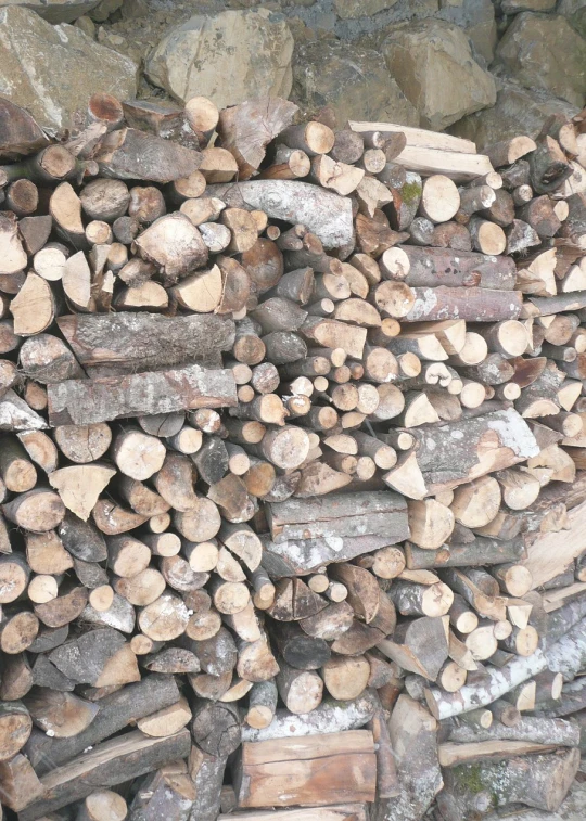 stacks of wood and logs stacked together by the road