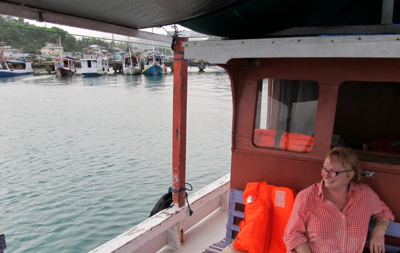 a woman sitting on the bow of a boat looking out over water