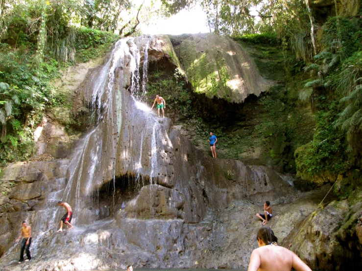 people are jumping in the water from a waterfall