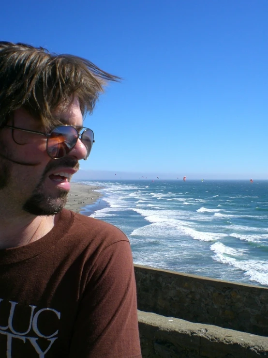 a man stands at the ocean while looking down