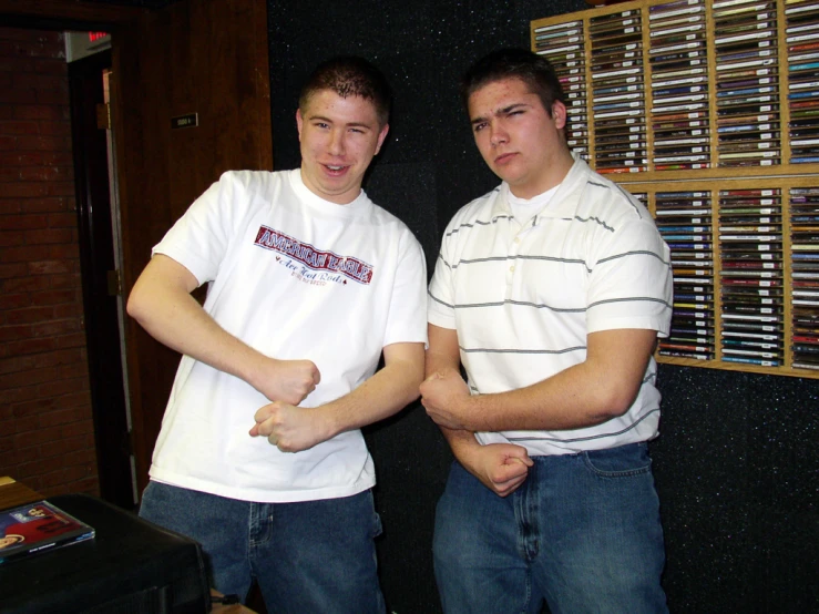 two men standing next to each other holding remotes