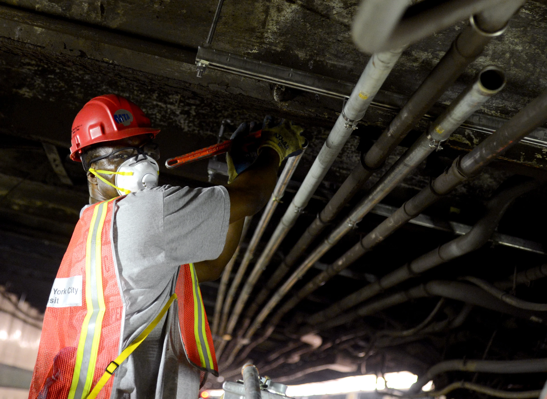 construction worker with hard hat and safety vest fixing pipes