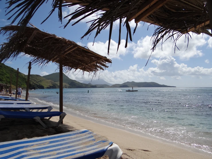 the beach has blue and white  umbrellas and lounge chairs