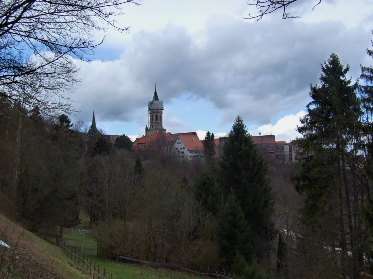 a town and church sitting on a hill surrounded by trees