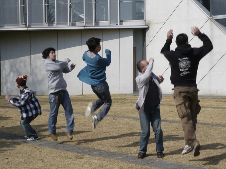 six people jump in the air in front of a building