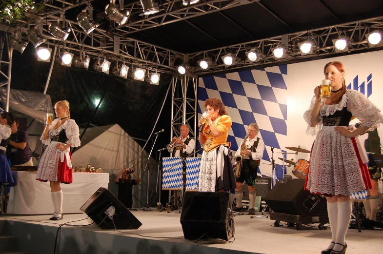 two ladies stand on a stage singing to music