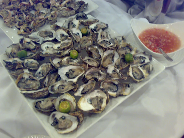 oysters are served with a dipping sauce on a table