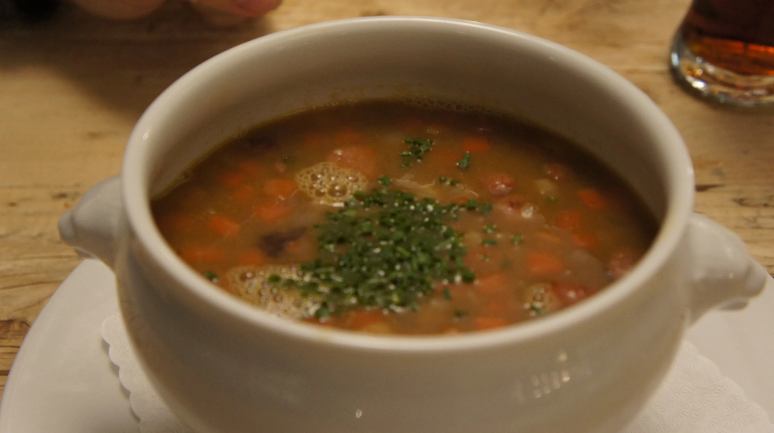 a soup dish sits on the table, with a beverage