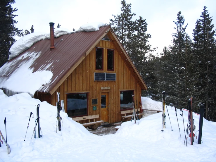 a log house surrounded by snow and skis