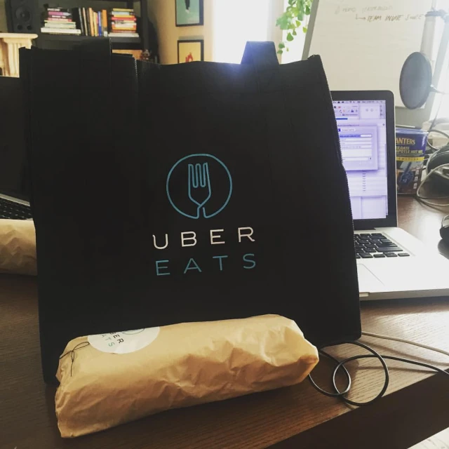 a close up of a bag on a desk with a laptop in the background