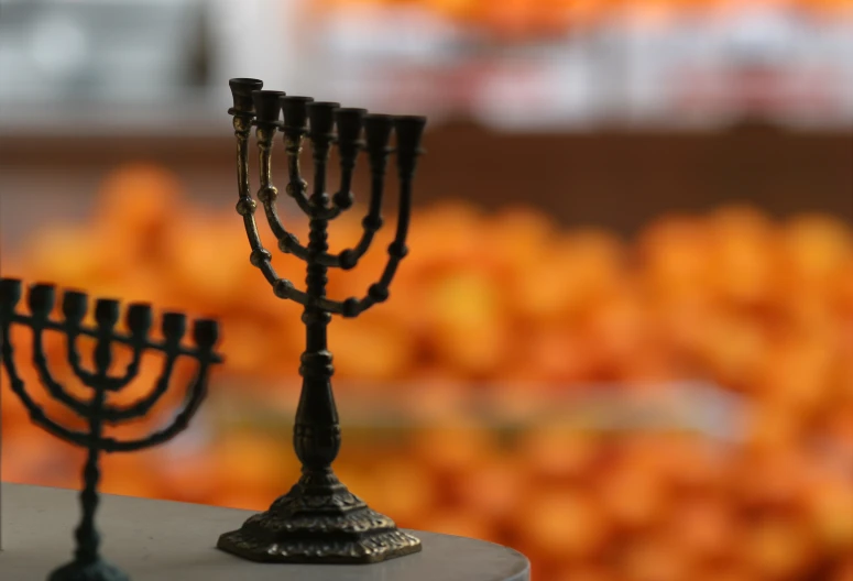 two candles sitting side by side in front of oranges