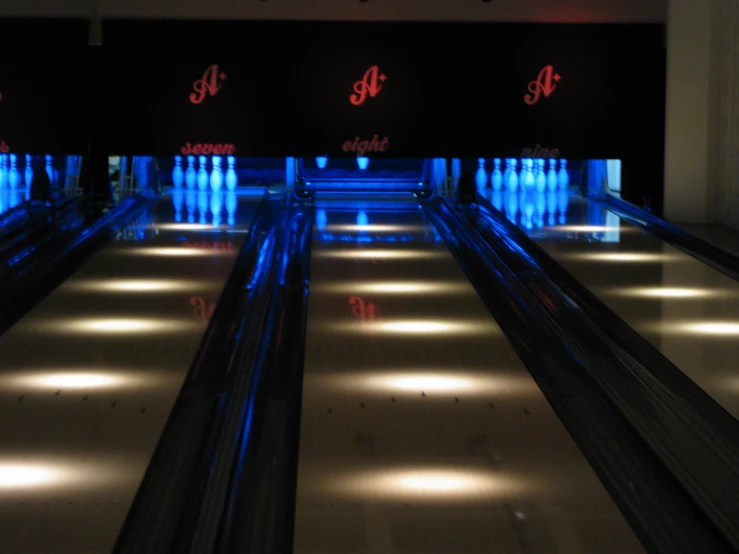 a bowling alley has blue lighted bowling pins