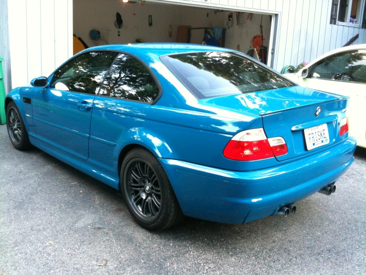 the back of a blue bmw car parked in front of a garage