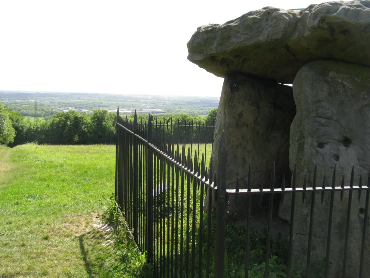 rock pillars and fences on a field of grass with hills in the background